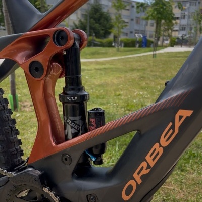 Quadro de bicicleta de montanha preto e laranja com suspensão traseira e logo ORBEA