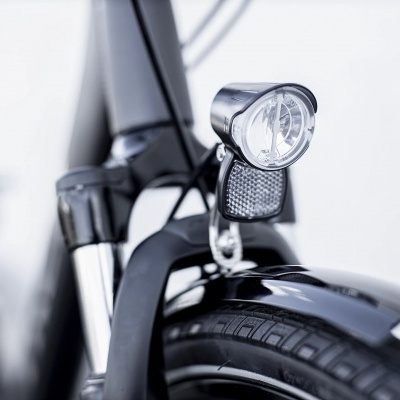 Foco frontal e detalhe da roda de bicicleta preta com farol cromado e refletor