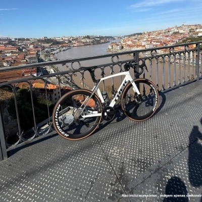 Bicicleta de estrada branca TREK junto a grade metálica com vista para cidade e rio