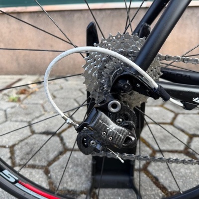 Mudança de velocidades traseira de bicicleta em carbono SUPER RECORD com corrente e roda preta num pavimento de calçada portuguesa