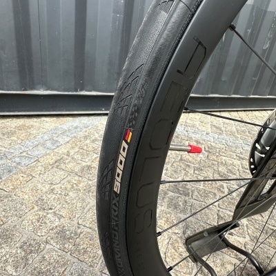 Pneu de bicicleta preto Schwalbe Pro One TLE em roda preta com válvula vermelha