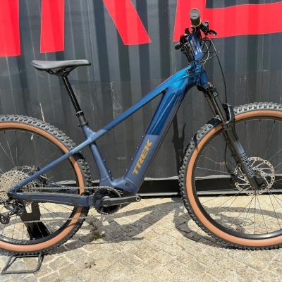 Bicicleta de montanha elétrica azul com pneus castanhos Bontrager e suspensão RockShox
