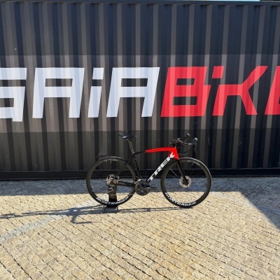 Bicicleta de estrada preta e vermelha encostada numa parede escura com texto GAIABIKE