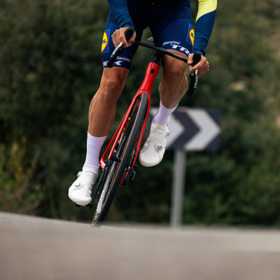 Ciclista equipado com roupa azul LIDL a andar de bicicleta vermelha na estrada