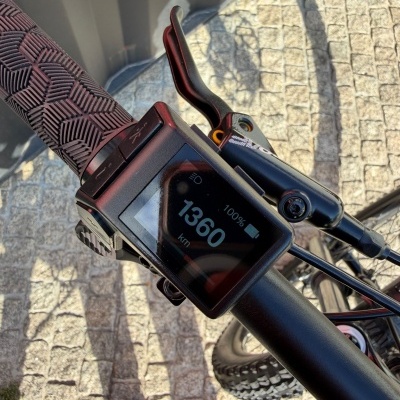 Punho de bicicleta com display digital e manete de travão preto sobre calçada