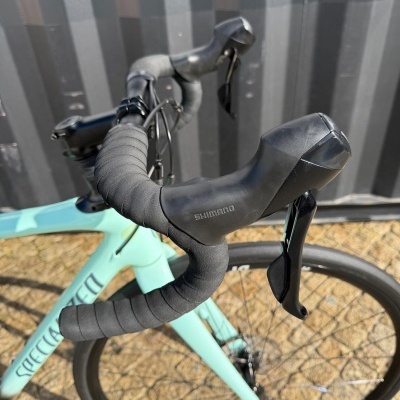 Guiador de bicicleta de estrada azul claro com manetes Shimano e roda DT SWISS.