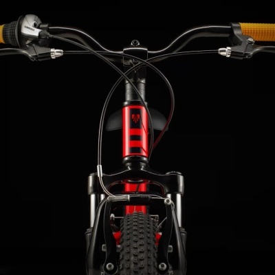 Bicicleta vermelha e preta com punhos amarelos em fundo preto