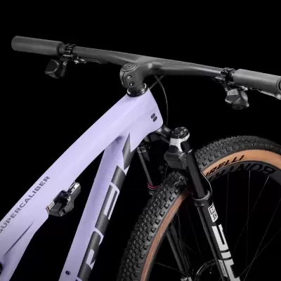 Bicicleta de montanha quadro lilás e preto, guiador preto e pneus castanhos