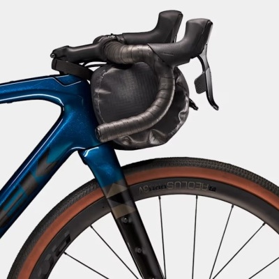 Parte frontal de bicicleta azul com bolsa preta no guiador e pneu marrom