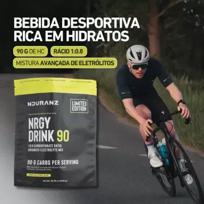 Embalagem de bebida desportiva Nduranz NRGY DRINK 90 ao lado de ciclista a pedalar na estrada