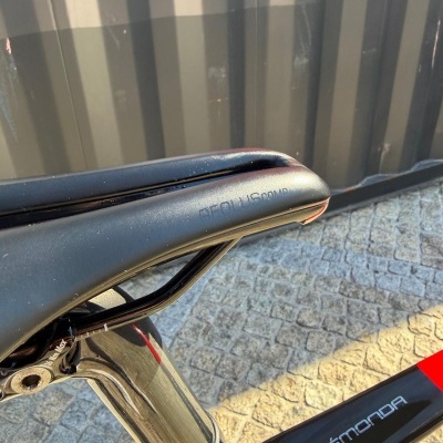 Selim preto de bicicleta com gravação AROUSUS COMP no quadro preto ÉMONDA ao ar livre sobre calçada