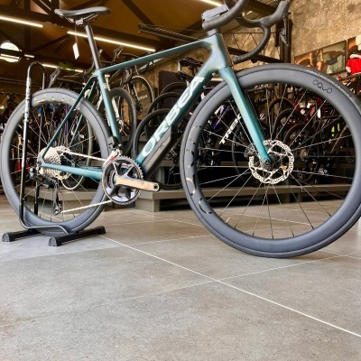 Bicicleta de estrada Orbea azul esverdeada numa loja com paredes de pedra