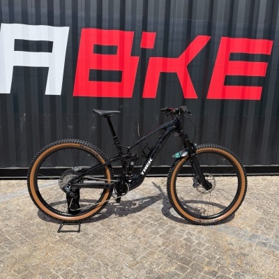 Bicicleta de montanha preta e castanha junto a parede com letras vermelhas e brancas