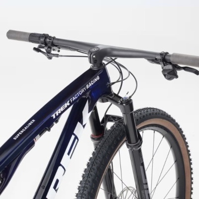 Bicicleta de montanha azul escuro com detalhes brancos e pneus com cravos