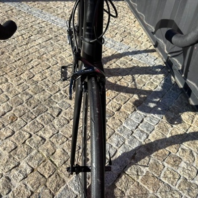 Bicicleta de estrada preta com travão Shimano Tiagra dianteiro no pavimento de calçada portuguesa