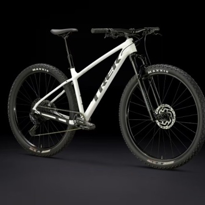 Bicicleta de montanha branca e preta com pneus Maxxis sobre fundo preto