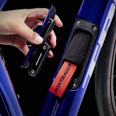 Bicicleta azul com compartimento interno aberto e ferramenta preta compacta na mão