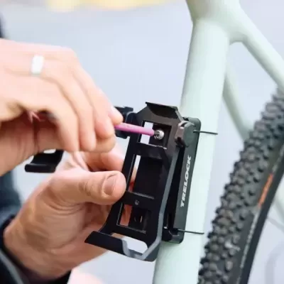 Suporte de telemóvel preto a ser instalado numa bicicleta cinza claro com pneus de cravos