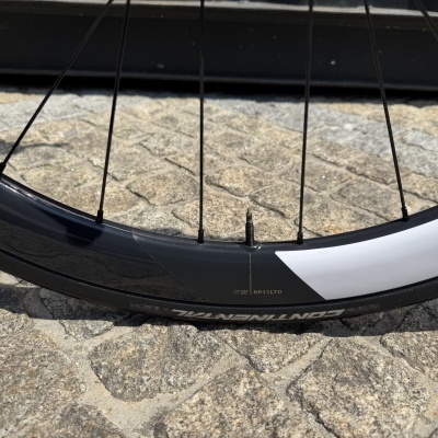 Roda de bicicleta preta e branca com raios pretos e pneu Continental