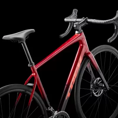 Bicicleta de estrada vermelha metálica com selim, guiador e rodas pretas em fundo preto