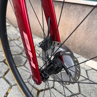 Roda dianteira de bicicleta vermelha com disco de travão e cubo preto