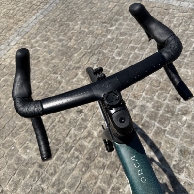Bicicleta de corrida com guiador preto e quadro verde escuro com a palavra ORCA