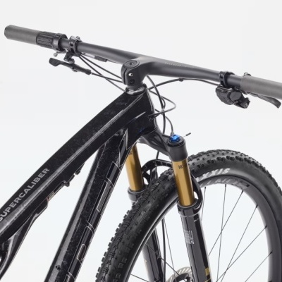 Bicicleta preta Trek Supercaliber com suspensão Fox e guiador cinza