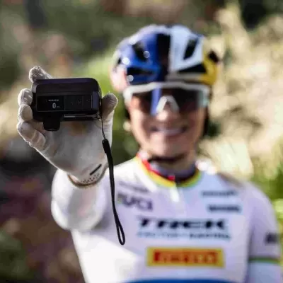 Ciclista com equipamento branco segurando dispositivo eletrônico preto ao ar livre