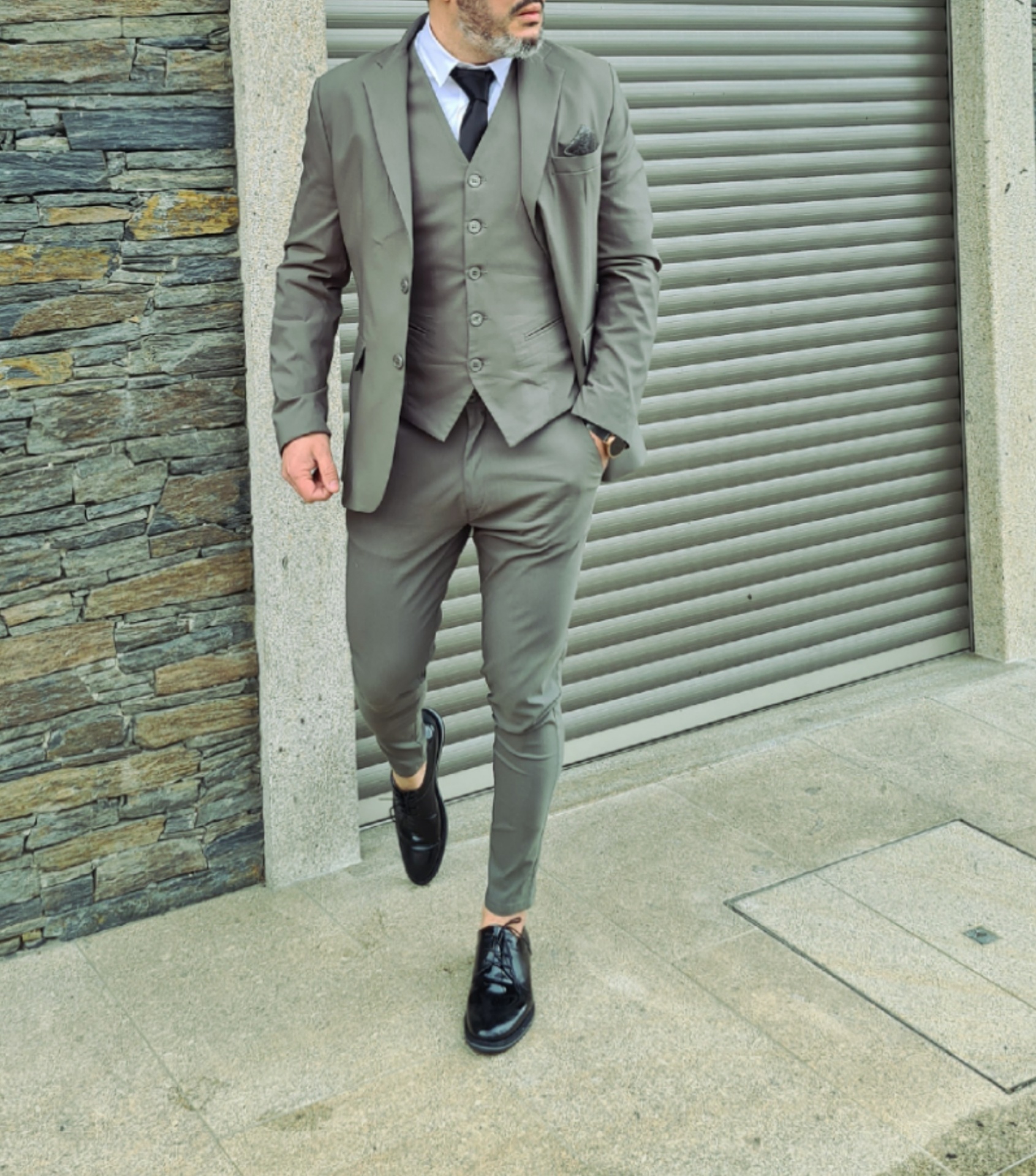 Homem com fato cinza e sapatos pretos em ambiente urbano