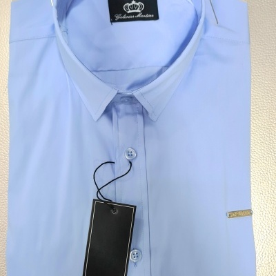 Camisa azul clara Gabrius Martins dobrada com etiqueta preta