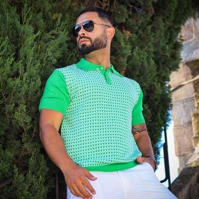 Homem com camisola verde e branco e calças brancas ao ar livre