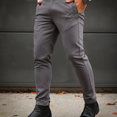 Calças cinza justas com cinto preto e botas pretas em fundo cinza