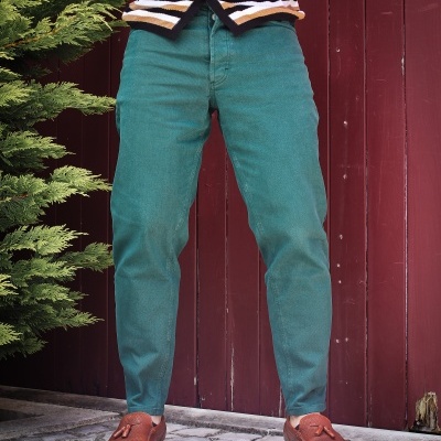 Calças verdes justas com mocassins castanhos e camisola às riscas em fundo vermelho