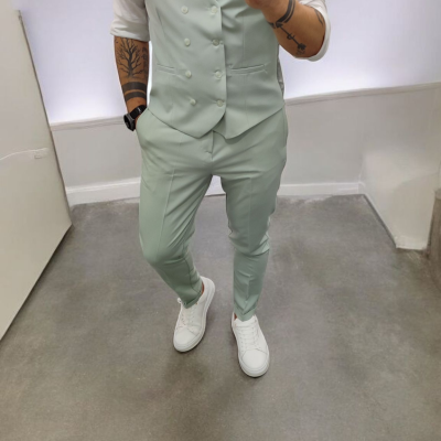 Homem com fato verde claro, camisa branca, gravata azul e sapatilhas brancas