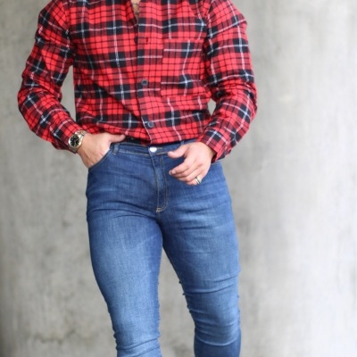 Homem com camisa xadrez vermelha e calças de ganga azuis, sapatos castanhos e óculos de sol