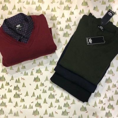 Duas camisas masculinas dobradas sobre tecido com padrão de árvores verdes