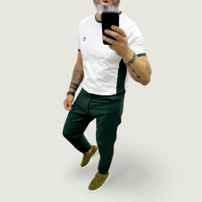 Homem de camisa branca e calças verdes escuros a tirar selfie