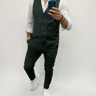 Homem com colete preto, camisa branca e ténis brancos a tirar selfie com smartphone.