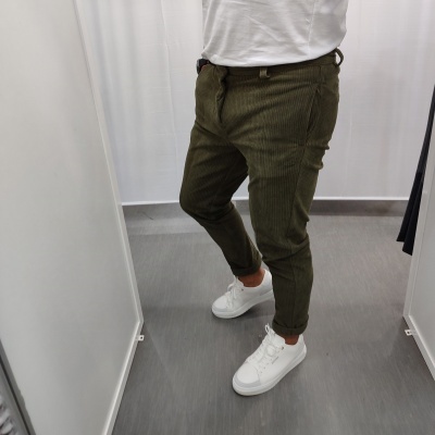 Homem a usar calças verdes de veludo cotelê, ténis brancos e t-shirt branca.