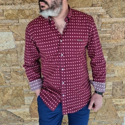 Camisa vermelha de padrão geométrico com punhos dobrados e calças azuis