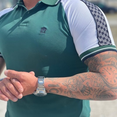 Polo verde com mangas brancas e padrão em faixa preta e branca nas mangas