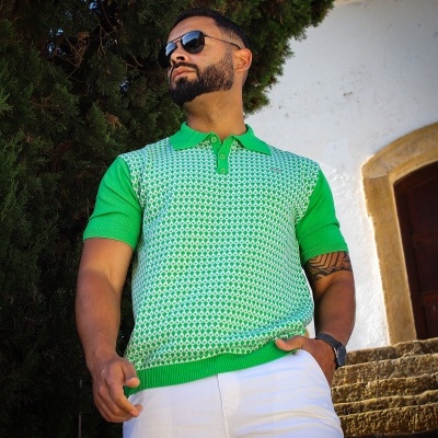 Homem a usar camisa polo verde com padrão geométrico e calças brancas em exterior