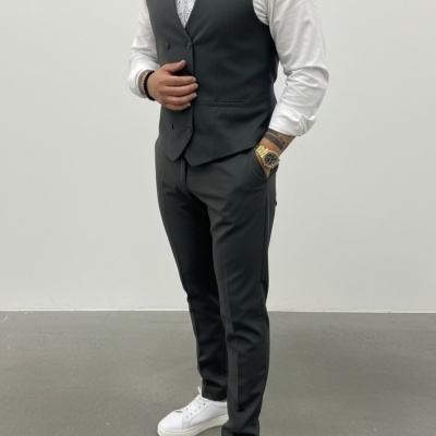 Homem a usar fato preto com colete, camisa branca e ténis brancos