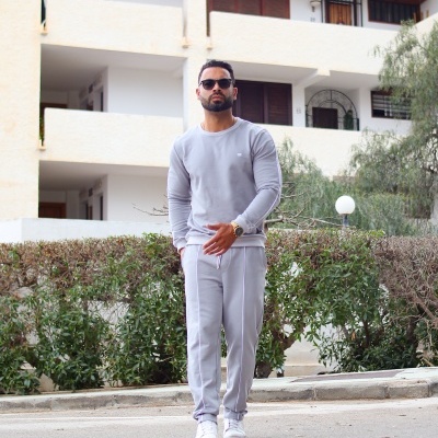 Homem com conjunto desportivo cinzento claro e óculos de sol