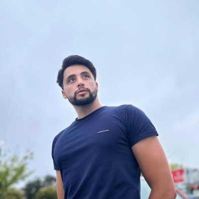 Homem com t-shirt azul escura em ambiente exterior nublado