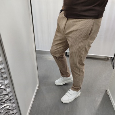 Pessoa a usar calças às riscas e sapatilhas brancas dentro de um provador.