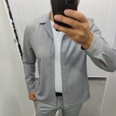 Homem a tirar selfie com casaco e calças cinza riscado e t-shirt branca