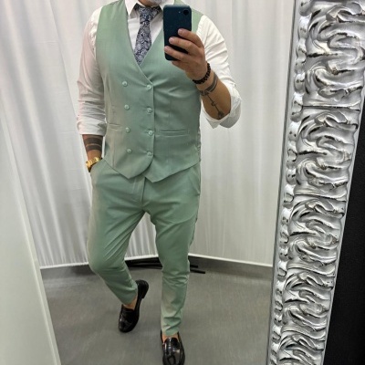 Homem vestido com fato verde claro em espelho com moldura prateada