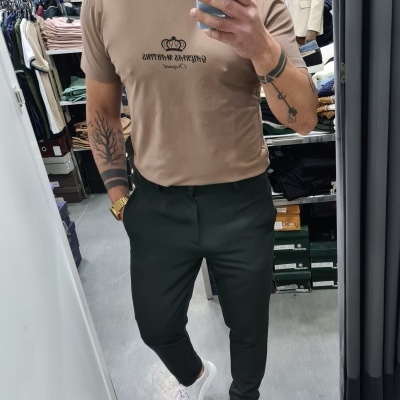 Homem com t-shirt bege e calças escuras a tirar selfie numa loja de roupas