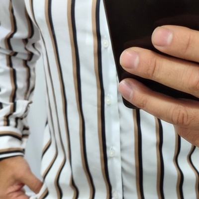 Camisa branca com riscas verticais castanhas e pretas e botões brancos.